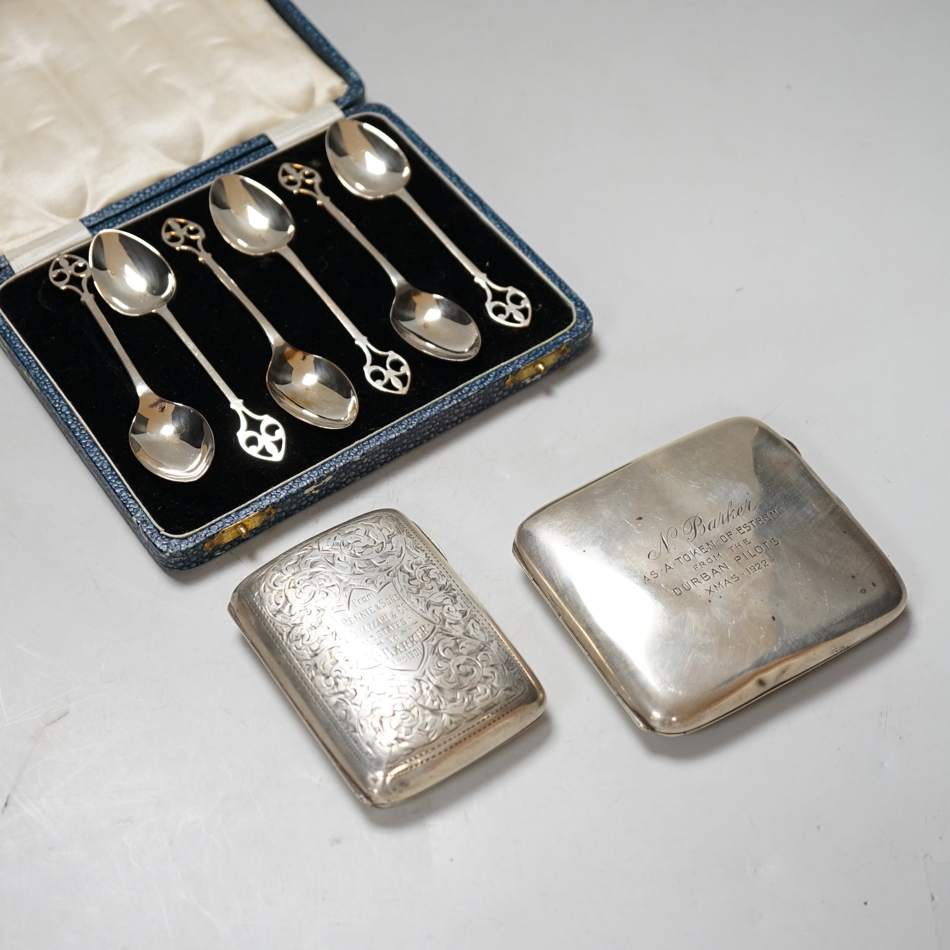 An Edwardian engraved silver cigarette case, 1901, 76 grams, a George V cigarette case with inscription from the Durban Pilots 1922, 102 grams and a cased set of six George V teaspoons, 58 grams